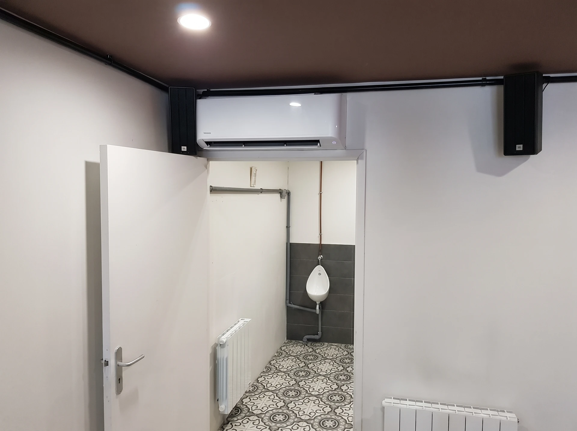 Plombier en uniforme bleu installant un radiateur à ailettes blanches dans une maison en construction